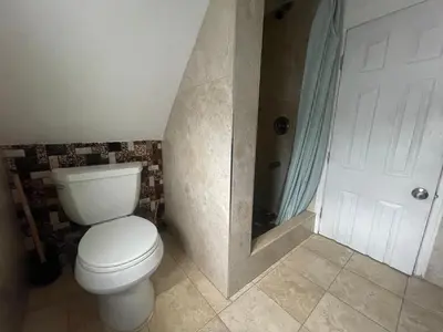 a bathroom with a white toilet and a shower at Private Loft 5 min away from LGA in East Elmhurst