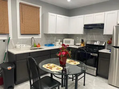 a kitchen with a small table and a kitchen with white cabinets at Cozy Getaway Room in Newark