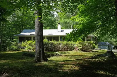 a house in the middle of a yard with a tree at Enchanted Woodstock Cottage with hot tub in West Hurley