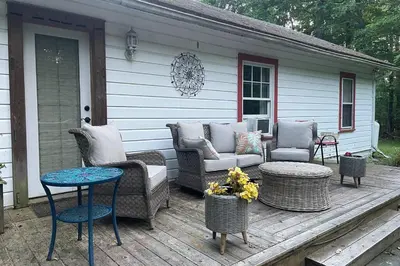 a porch with a couch and chairs on a deck at Enchanted Woodstock Cottage with hot tub in West Hurley