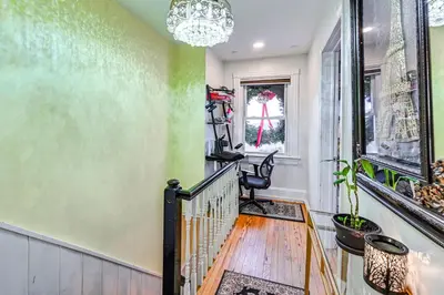 a hallway with a staircase and a chandelier at Welcoming Glen Cove Home about 1 Mi to Public Beach! in Glen Cove