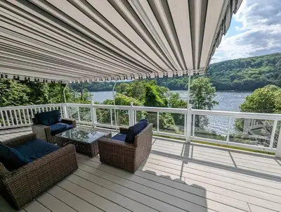 a porch with chairs and a table and a view of the water at Candlewood Lake -Family Getaway, Lakefront 3775 sqft Home in Danbury