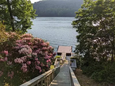 a house on the shore of a lake with flowers at Candlewood Lake -Family Getaway, Lakefront 3775 sqft Home in Danbury