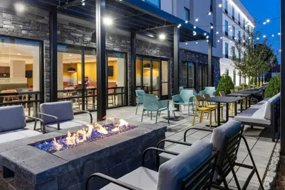 a fire pit on a patio with chairs and tables at Home2 Suites By Hilton East Haven New Haven in East Haven