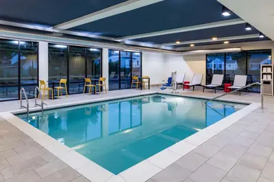 a swimming pool with chairs and tables in a building at Home2 Suites By Hilton East Haven New Haven in East Haven