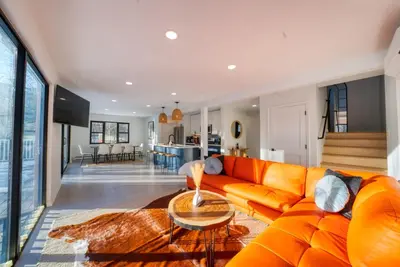 an orange couch in a living room with a table at Brand New House with Huge Patio in Kerhonkson