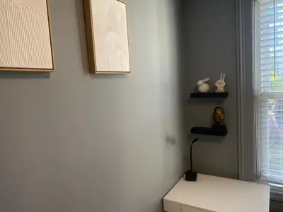 a corner of a room with a white wall with two shelves at Cozy apartment with city skyline. Easy commute midtown Manhattan. in Jersey City