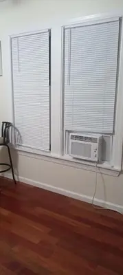 a room with a window with a air conditioner and a window with a fan at the rest spot in Schenectady