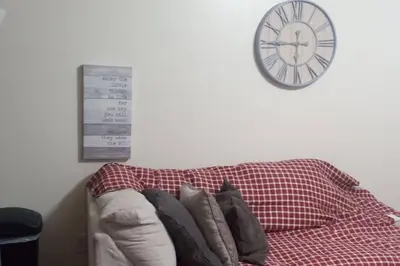 a clock on the wall above a couch with pillows at the rest spot in Schenectady