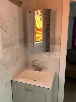 a white bathroom with a sink and a mirror at King Suite 8Mins to Newark Airport in Newark