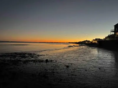 a view of a beach with the sun setting at Bobby's Beach Bungalow in Milford