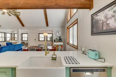 a kitchen with a sink and a living room at Family-Friendly Big Bass Lake Vacation Rental! in Gouldsboro