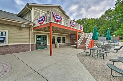 a playground with tables and umbrellas in front of a building at Family-Friendly Big Bass Lake Vacation Rental! in Gouldsboro