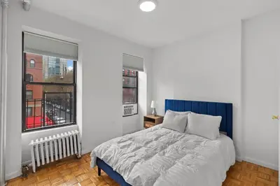 a bedroom with a blue bed and two windows at 89-3FS Newly Furnished 2br 1bath UES in New York