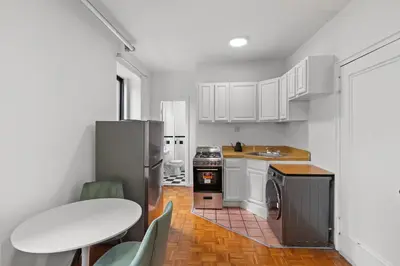 a kitchen with white cabinets and a table and a sink at 89-3FS Newly Furnished 2br 1bath UES in New York