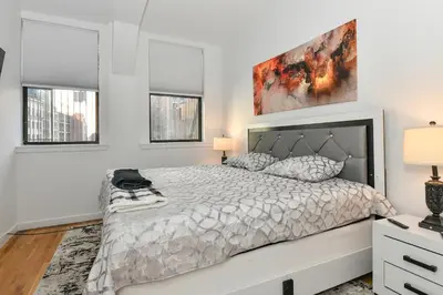 a white bedroom with a bed and two windows at Luxury 3 Bedroom Retreat in Downtown Manhattan in New York