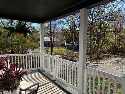 a porch with a white fence and a chair at Designer Home, Hot Tub, Private Yard, & Projector in Hudson