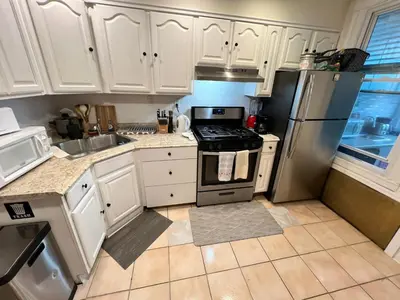 a kitchen with white cabinets and a stainless steel refrigerator at 7-A Diamond in Yonkers in Yonkers