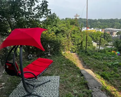 a red chair with a red umbrella in the grass at 7-A Diamond in Yonkers in Yonkers