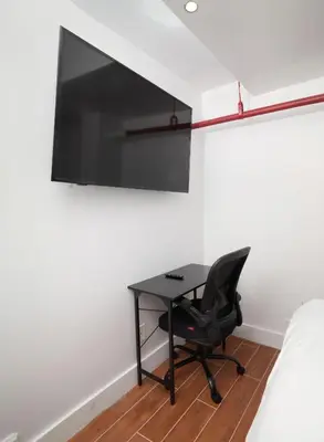 a desk with a chair and a tv on a wall at Comfy Guest House in Hell's Kitchen in New York