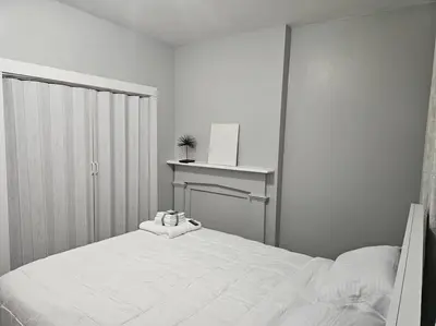 a white bedroom with a bed and a desk at Fortune Suits and Apartment in Albany