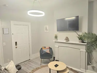 a living room with a chair and a flat screen tv at Fortune Suits and Apartment in Albany