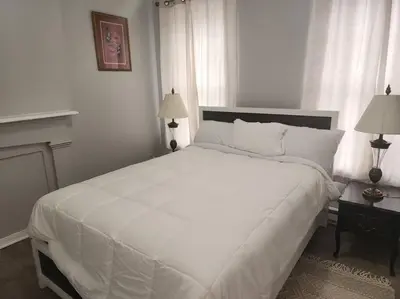 a bedroom with a large white bed with two lamps at Fortune Suits and Apartment in Albany