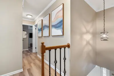 a hallway with white walls and stairs with paintings on the wall at Game Room+Hot Tub+Pool+King Beds+More in Gansevoort