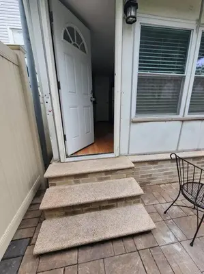 a front door of a house with a chair and stairs at Cozy studio in a lovely area in Forest Hills