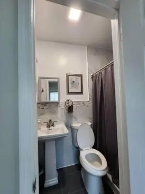 a bathroom with a white toilet and a sink at Cozy studio in a lovely area in Forest Hills