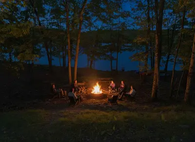 a group of people sitting around a fire at night at Lakefront, Game Rm, Arcade, Hot Tub, Pool, Pets in Bushkill
