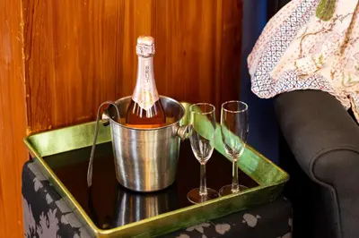 a bottle of wine in a bucket next to two wine glasses at Palazzo Hudson - Luxury Pool, Hot Tub, and Sauna in Hudson