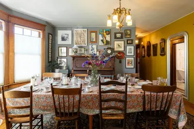 a dining room with a table with a vase of flowers on it at Palazzo Hudson - Luxury Pool, Hot Tub, and Sauna in Hudson