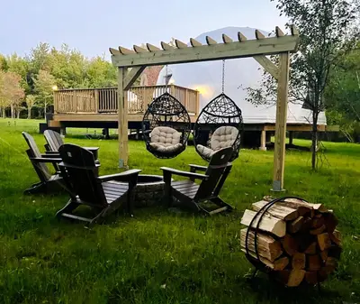 a gazebo with chairs and a swing in a yard at Unique Escapes - Nature Lovers Geodome in Monticello