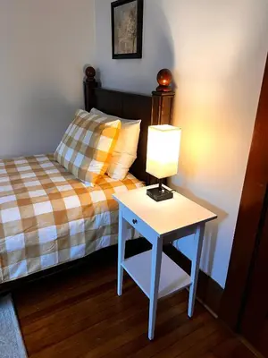 a bedroom with a bed and a table with a lamp at Comfortable and Tranquil -1st Fl in New Haven