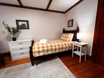 a bedroom with a bed and a dresser and a lamp at Comfortable and Tranquil -1st Fl in New Haven
