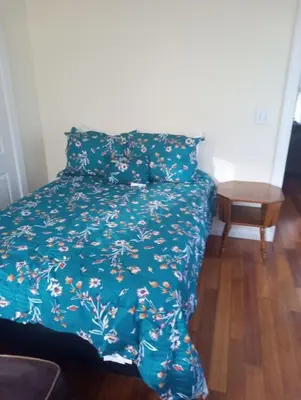 a bed with a blue comforter and a table at 1 bedroom with free parking in Schenectady