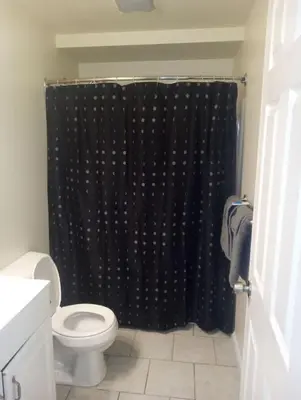 a bathroom with a black shower curtain and a toilet at 1 bedroom with free parking in Schenectady