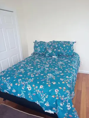 a bed with a blue bedspread with flowers on it at 1 bedroom with free parking in Schenectady