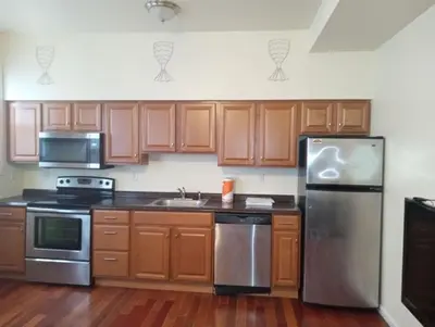 a kitchen with wooden cabinets and a stainless steel refrigerator at comfy cozy roomy in Schenectady