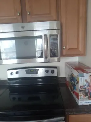 a microwave above a stove with a box in a kitchen at a nice one bedroom free parking in Schenectady