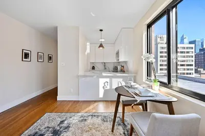 a white kitchen with a table and a large window at Modern one bedroom with private balcony in New York