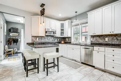 a kitchen with white cabinets and a island with stools at Elegant Saratoga Springs Stay Walk to Town, Track in Saratoga Springs