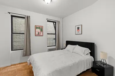 a white bedroom with a bed and two windows at Cozy 1BR in the Upper East Side in New York
