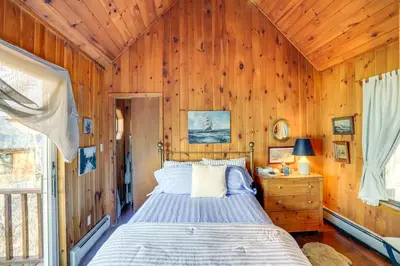 a bedroom with a bed and a wooden wall at Ski, Sip and Snuggle Cozy Catskills Gem with Views! in Athens