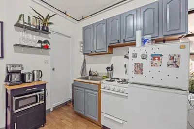 a kitchen with gray cabinets and a refrigerator at Steps from Everything - Modern 1-Bdr in Downtown's Union Square in New York