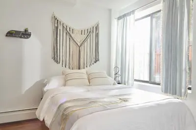 a white bedroom with a large bed and a window at American Dream Guest House in New York