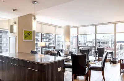a living room with tables and chairs and large windows at Spacious Apartment Downtown in Stamford