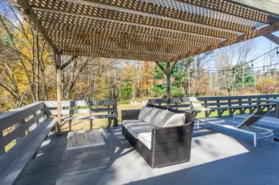 a pergola with a couch on a wooden deck at Catskills Delaware River Modern Colonial Getaway in Narrowsburg