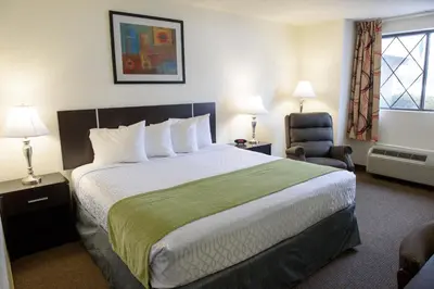 a hotel room with a large bed and a chair at Americas Best Value Inn New Paltz in New Paltz